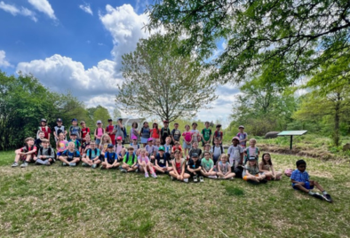  a group photo of students sitting in the grass at the park on a sunny day